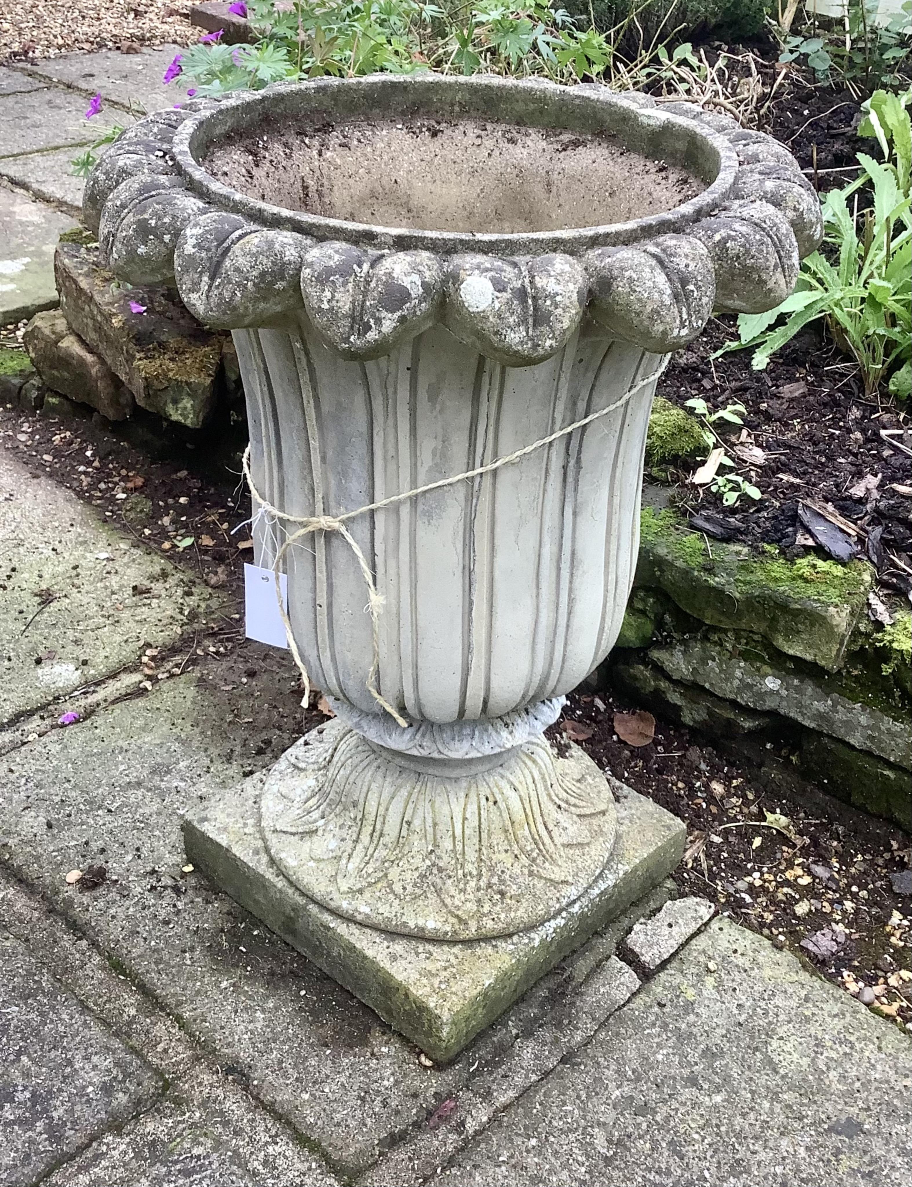 A pair of reconstituted stone tulip urns, height 66cm, depth 50cm, planting removed. Condition - weathered, otherwise good